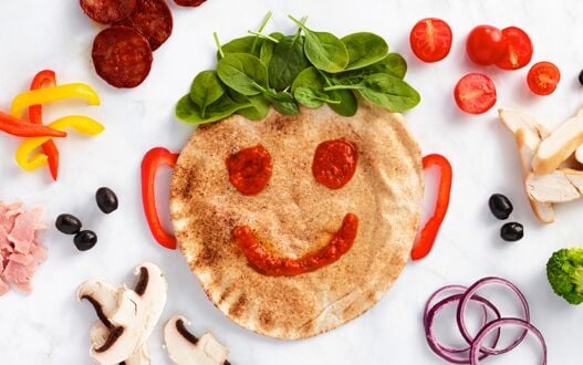 A pizza with a friendly smile in pepperoni and tomato sauce